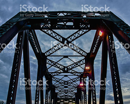 Medium sized photo of the CPR bridge in Red Deer, Alberta with an upward view of the darkening skies.

