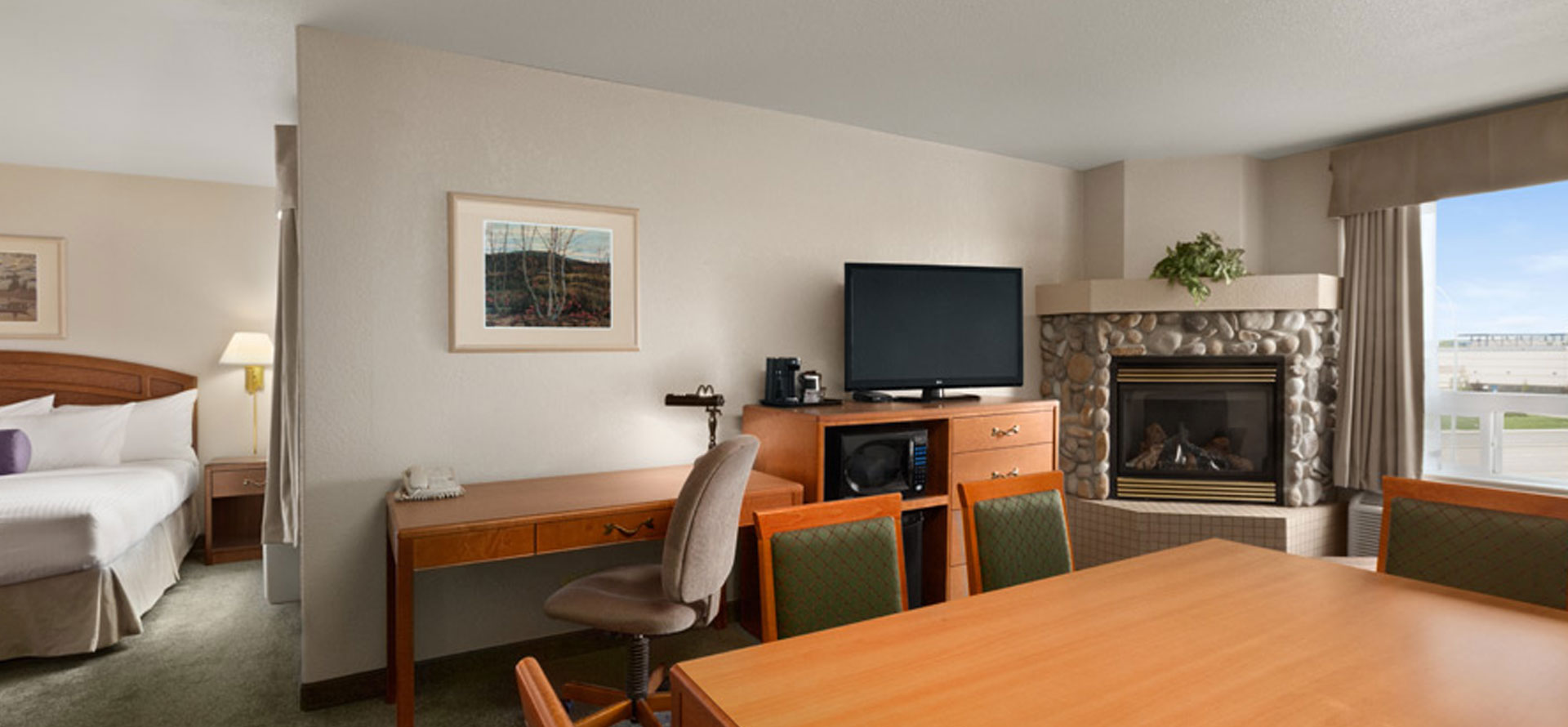 Business class suite with king sized bed, work desk, ergonomic chair, eating table and dining chairs at Days Inn Red Deer, Alberta.
               