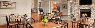 Small view of the Daybreak Café at Days Inn Red Deer, Alberta with eating tables, chairs and a stone fireplace.