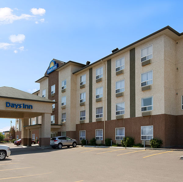 Parking lot view of Days Inn Red Deer, Alberta with a concrete portico covered entrance.