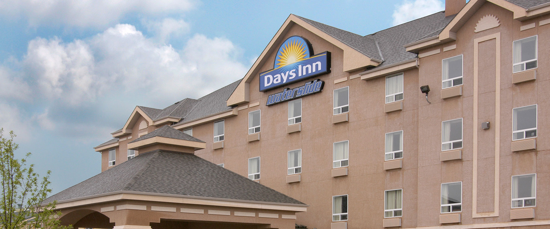 Large sized view of the exterior building of Days Inn Red Deer, Alberta with the company logo signage and a smaller sign that reads waterslide.
