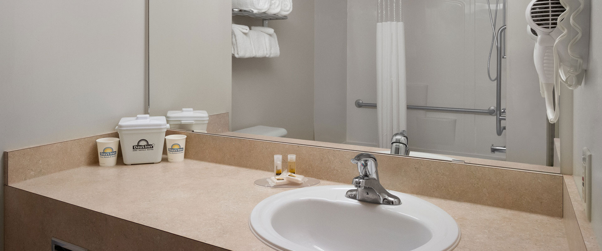 A typical bathroom suite at Days Inn Red Deer, Alberta features stocked linen, hair dryer, complimentary soap and paper cups with company logo.
