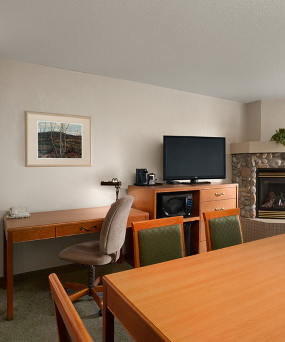 The work and entertaining area of a suite in Days Inn Red Deer, Alberta, with TV, work desks, microwave and stone fireplace.
               