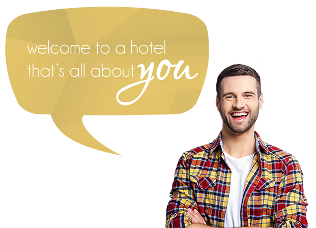 Smiling bearded man in a multi colored plaid shirt speaking through a speech bubble  Welcome to a hotel that's all about you.
