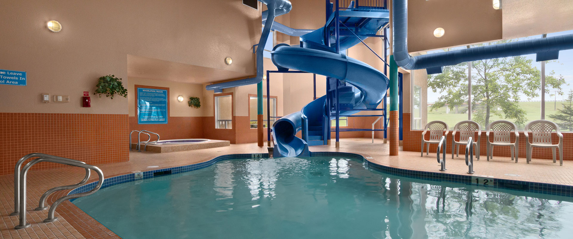 Heated indoor pool with a large waterslide and hot tub at Days Inn Red Deer, Alberta.
