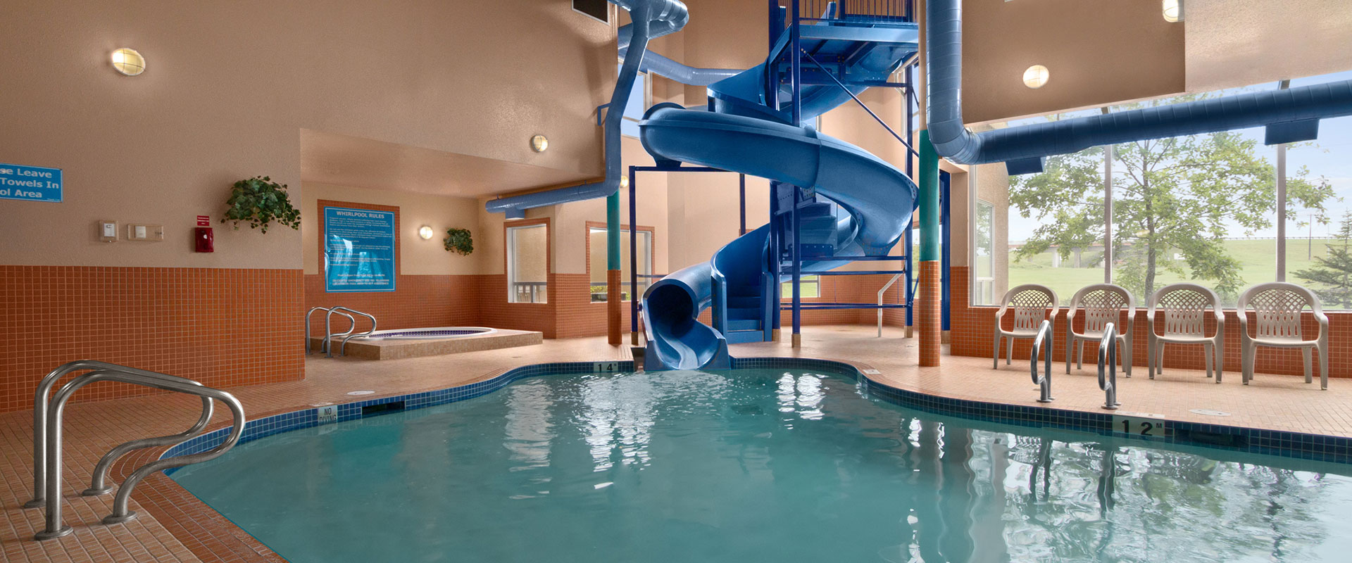 Heated indoor pool with a large waterslide and hot tub at Days Inn Red Deer, Alberta.
