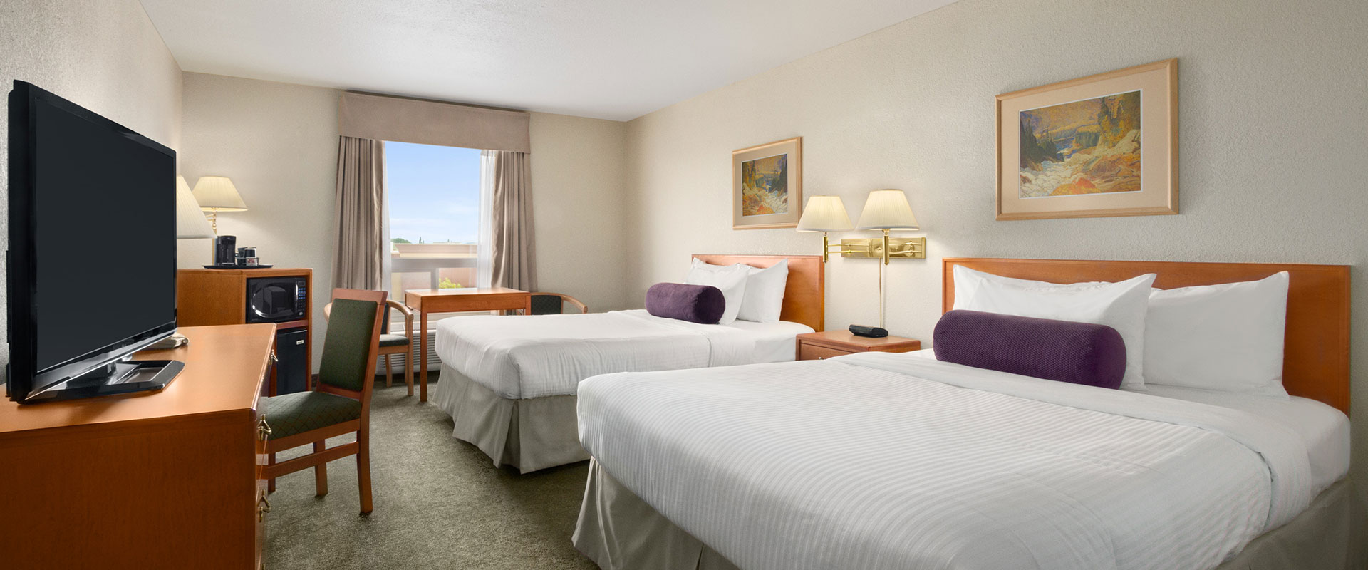 Two bed business class suite with microwave, TV, work table, lamps and chairs at Days Inn Red Deer, Alberta.
